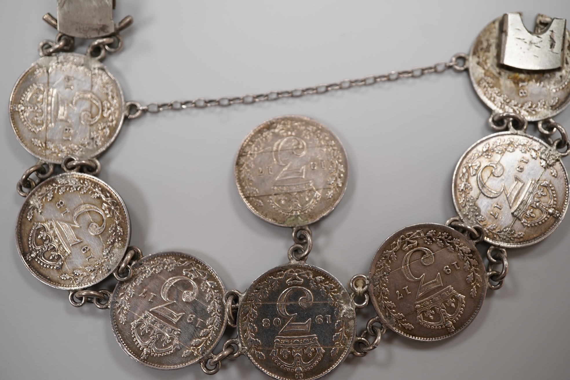 A cased early 20th century 9ct and single stone split pearl set bar brooch, 42mm and a white metal coin bracelet.